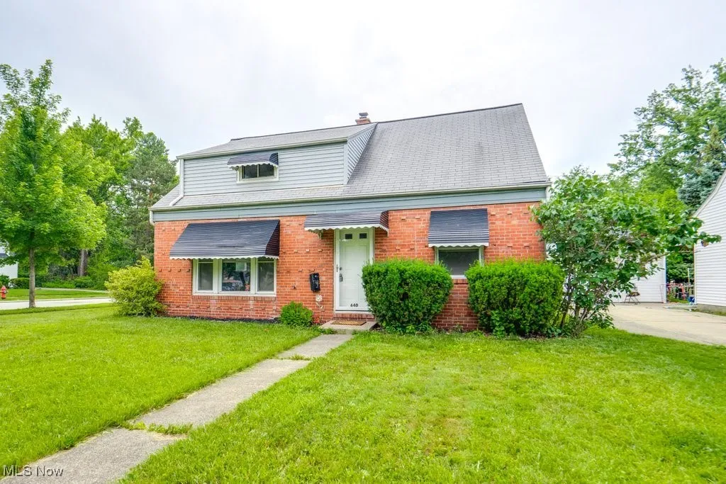 View of front of home featuring brick siding, a front lawn, and a chimney