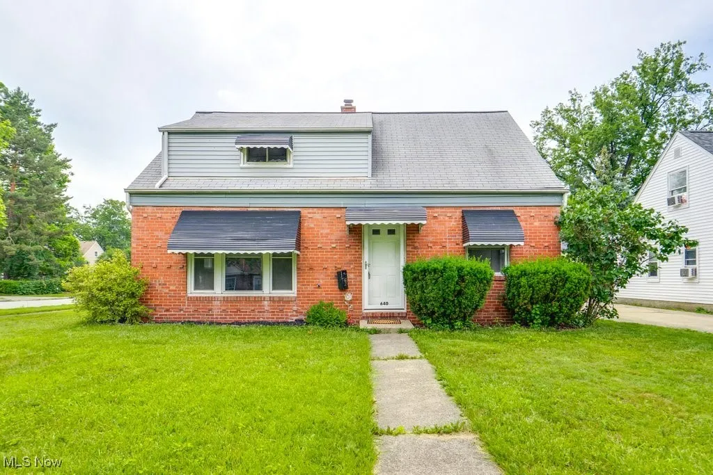 Bungalow-style house featuring brick siding, a front yard, and a chimney