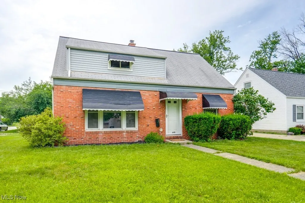 View of front facade featuring brick siding, a front lawn, and a chimney