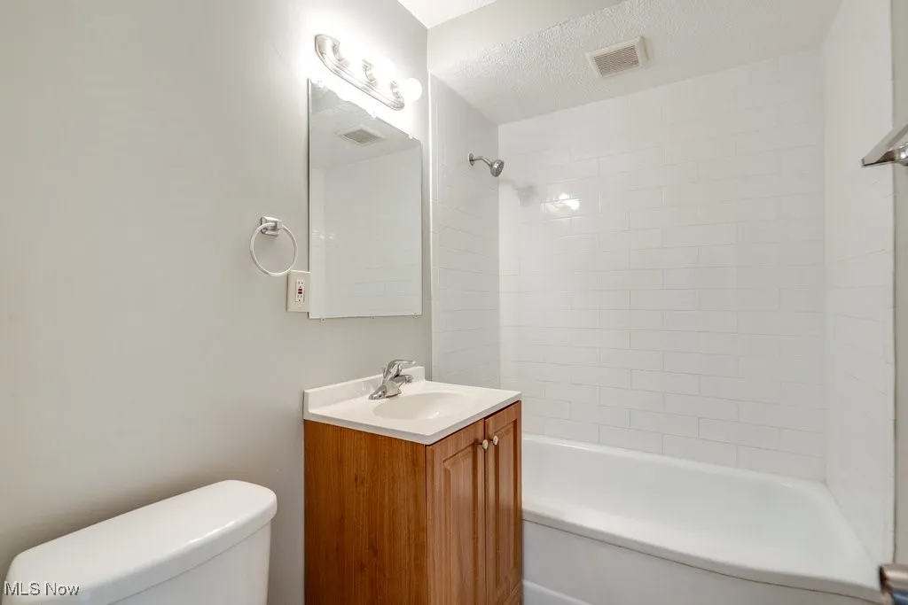 Bathroom with vanity, shower / washtub combination, and a textured ceiling