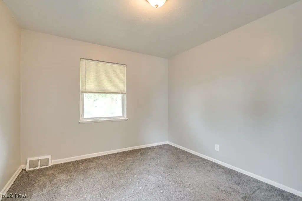 Carpeted spare room featuring baseboards