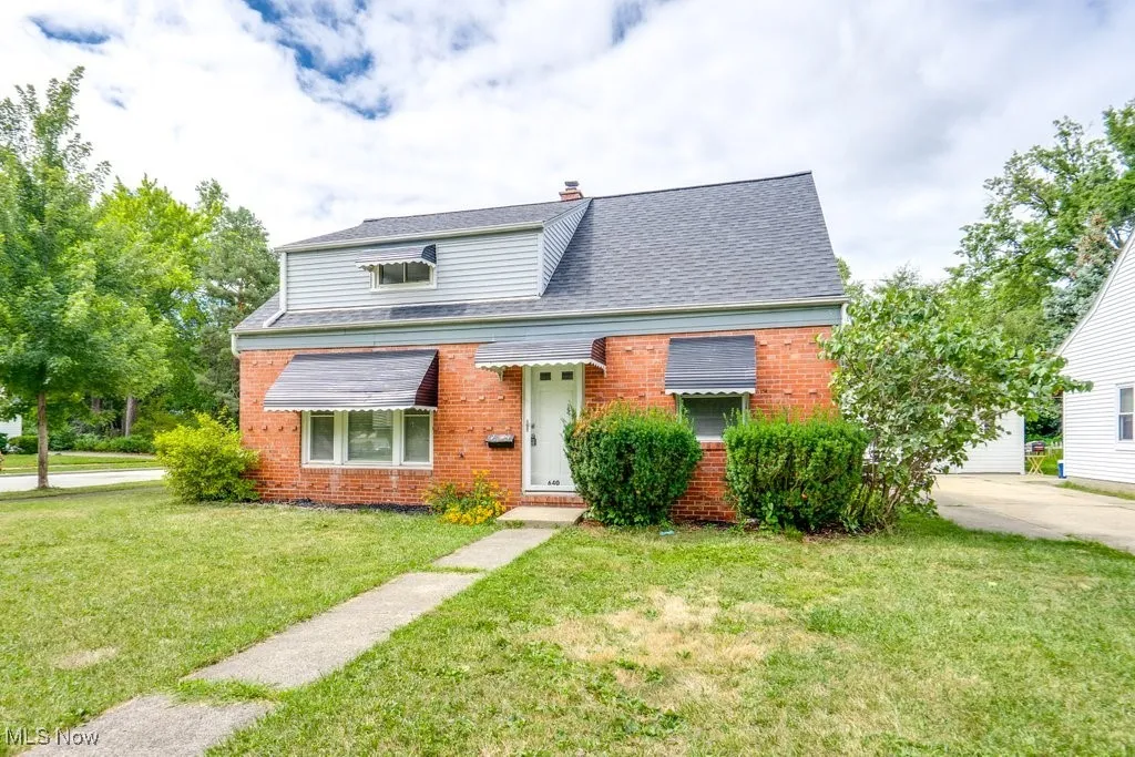 Bungalow-style home featuring a front yard, brick siding, a shingled roof, and a chimney