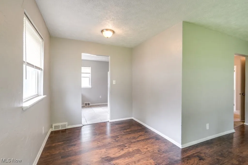 Unfurnished room with a textured ceiling and wood finished floors