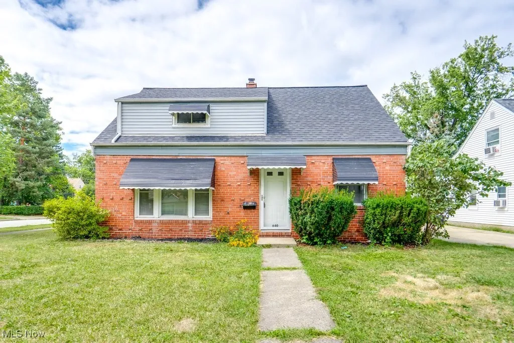 Bungalow-style house with a chimney, brick siding, and a front yard
