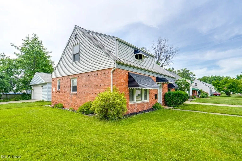 View of home's exterior with brick siding, a detached garage, a yard, and an outdoor structure
