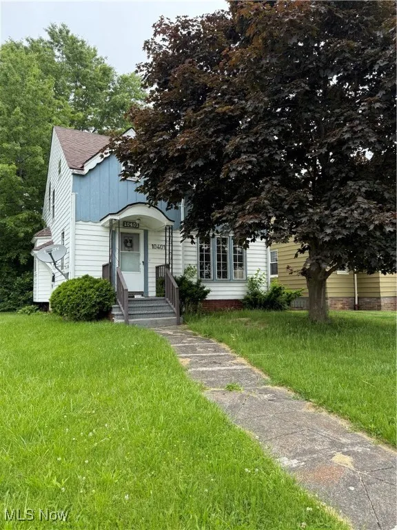 View of front of home with a front yard and roof with shingles