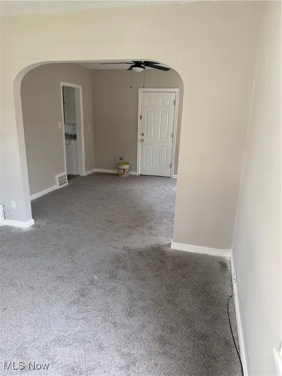 Spare room featuring arched walkways, a ceiling fan, and carpet