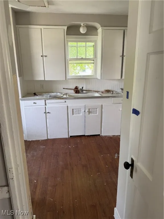 Kitchen featuring dark wood-style flooring, white cabinets, and light countertops