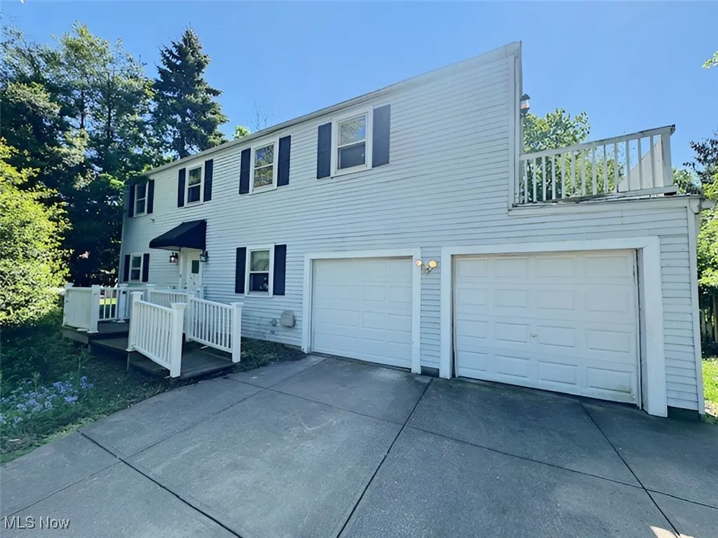 View of front facade featuring an attached garage, concrete driveway, and a wooden deck