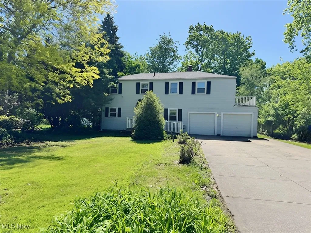 Colonial house with a garage, driveway, a front lawn, and a balcony