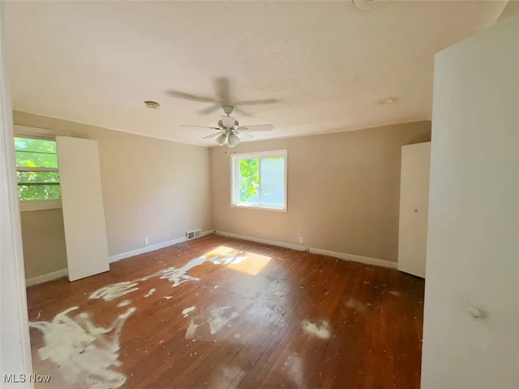 Unfurnished room featuring hardwood / wood-style floors, a ceiling fan, and a smoke detector