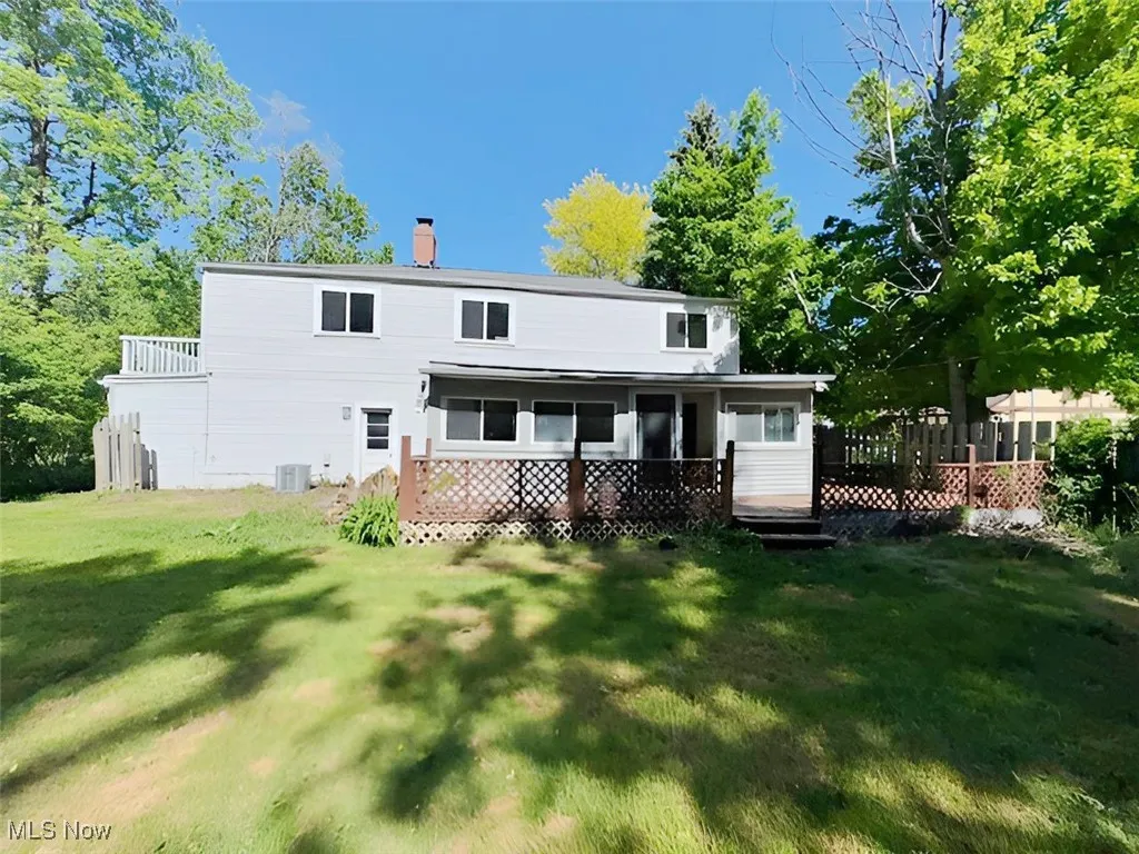 Rear view of house with a chimney, a sunroom, and a deck