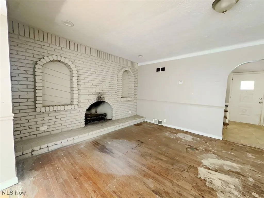 Unfurnished living room featuring hardwood / wood-style floors and arched walkways
