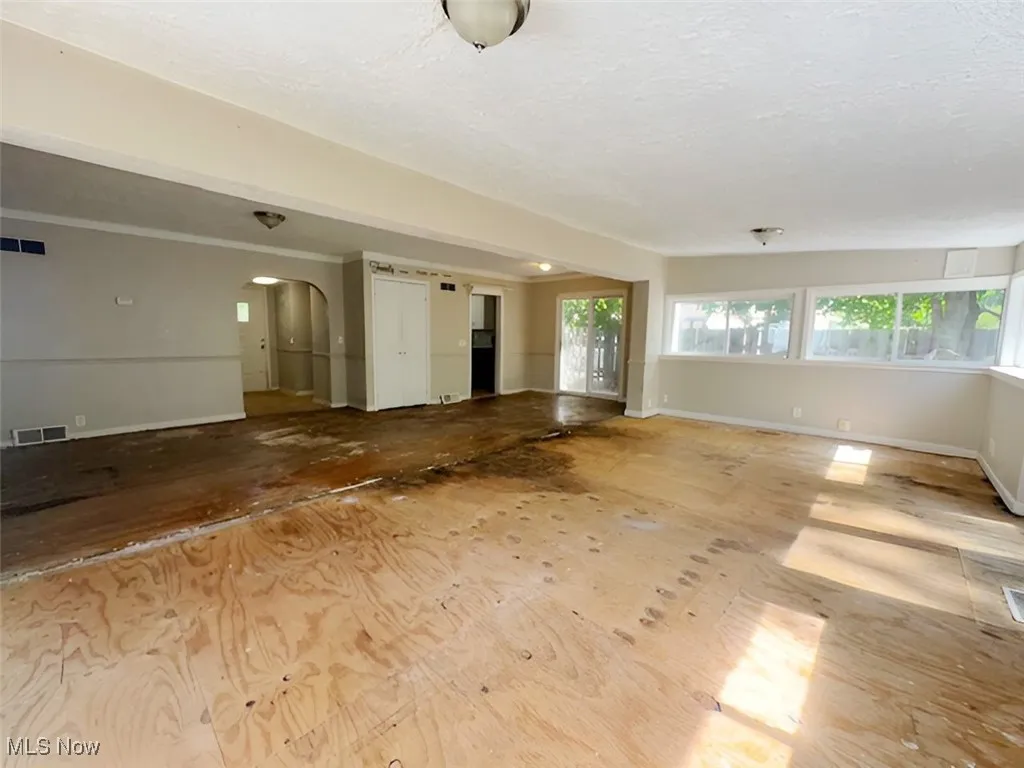 Unfurnished living room featuring arched walkways and a textured ceiling