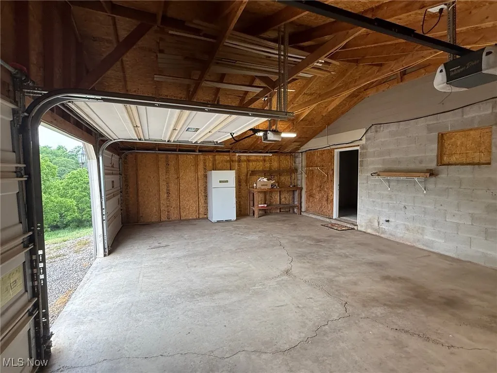 Garage featuring a garage door opener and freestanding refrigerator