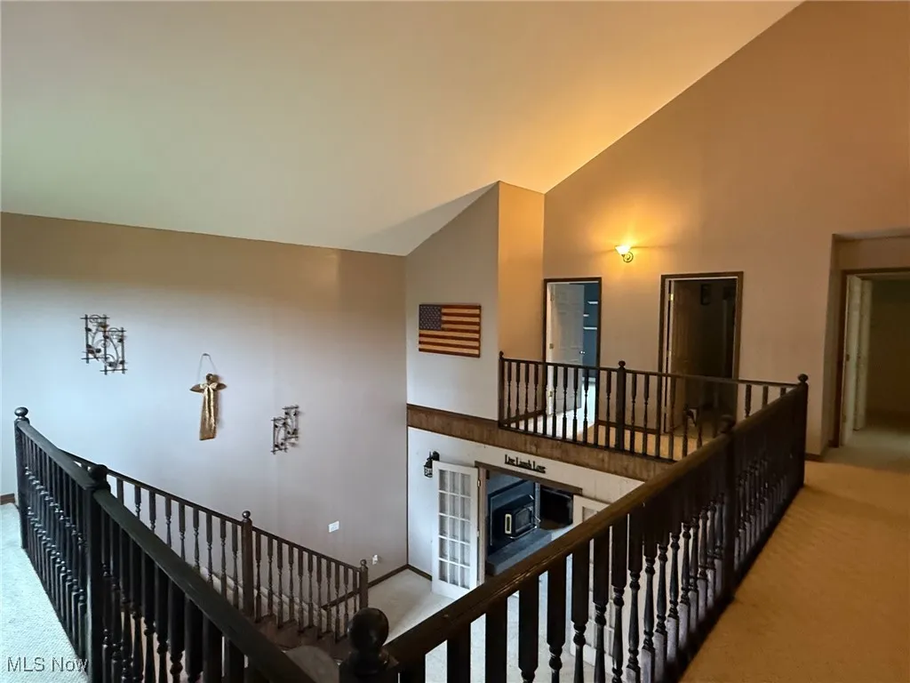Hall featuring carpet, an upstairs landing, and high vaulted ceiling