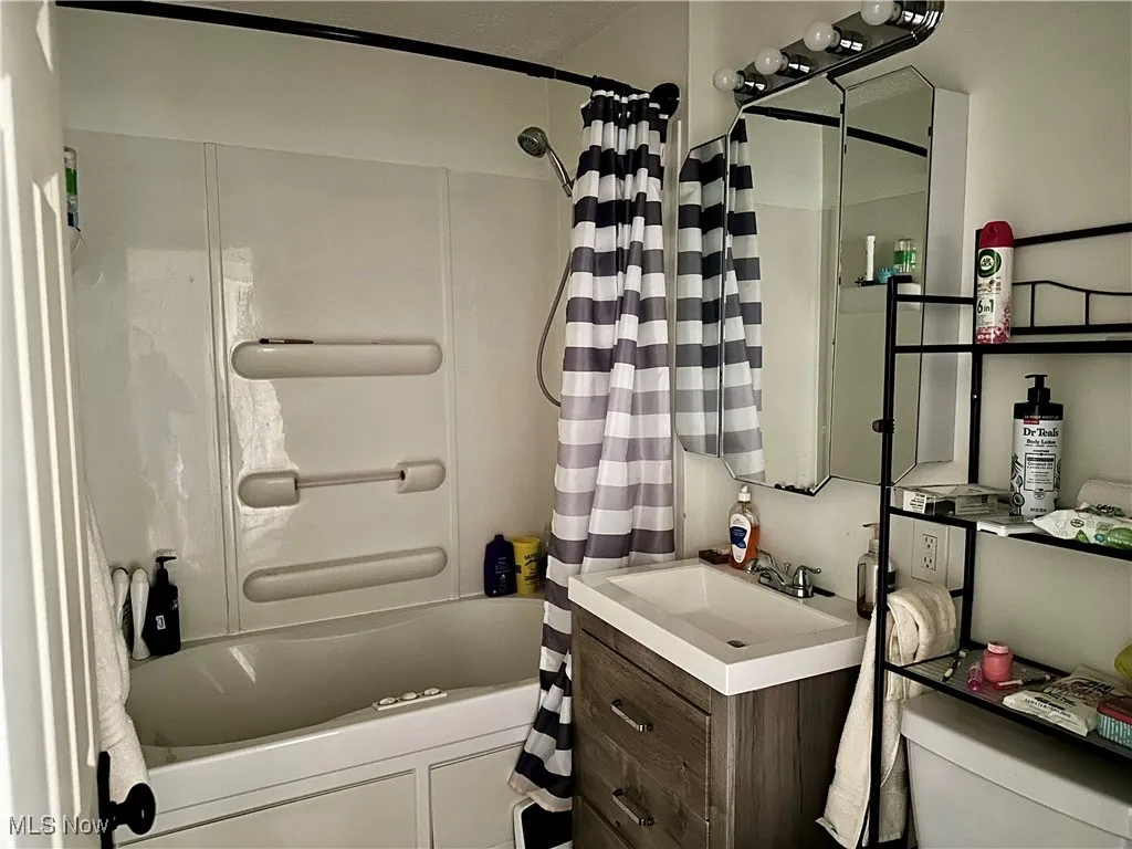 Bathroom with shower / bath combination with curtain and vanity