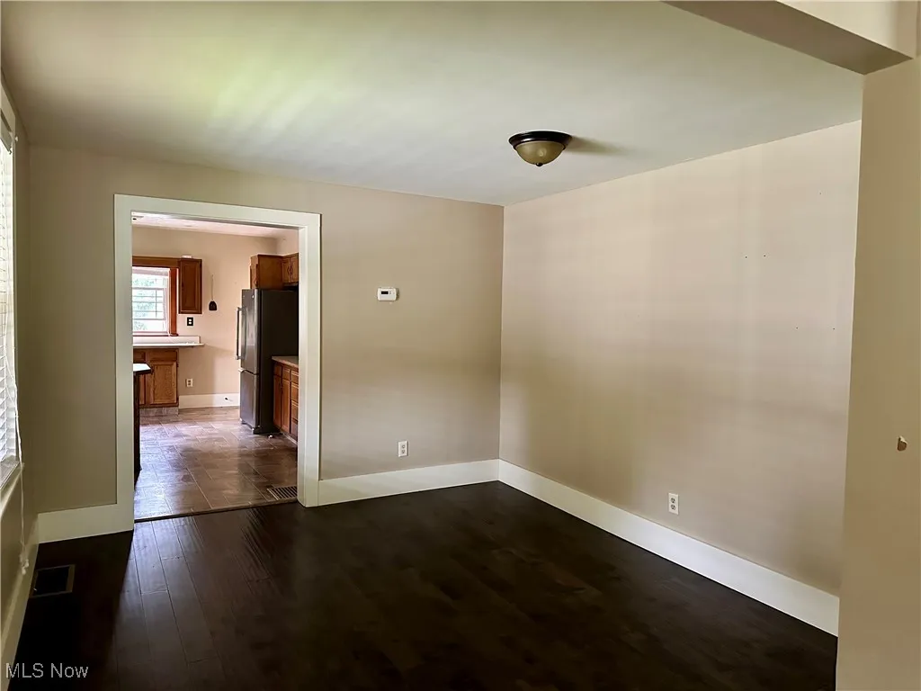 Spare room with dark wood-style flooring and baseboards