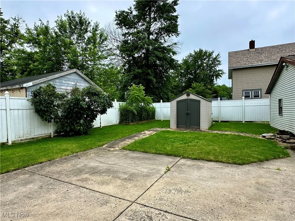 Fenced backyard with a storage shed and a patio area