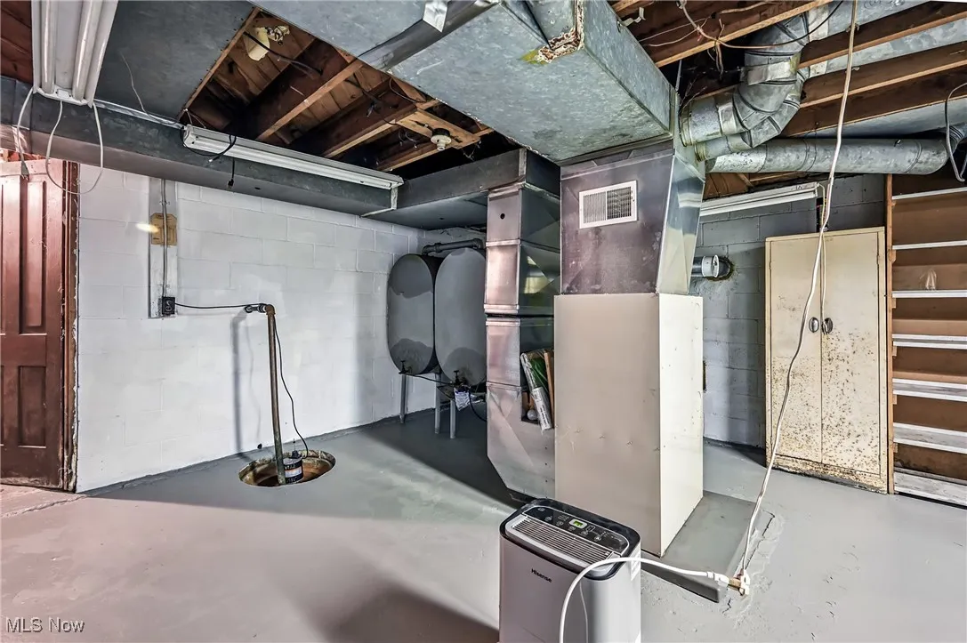 Unfinished below grade area with heating unit and drainage system
