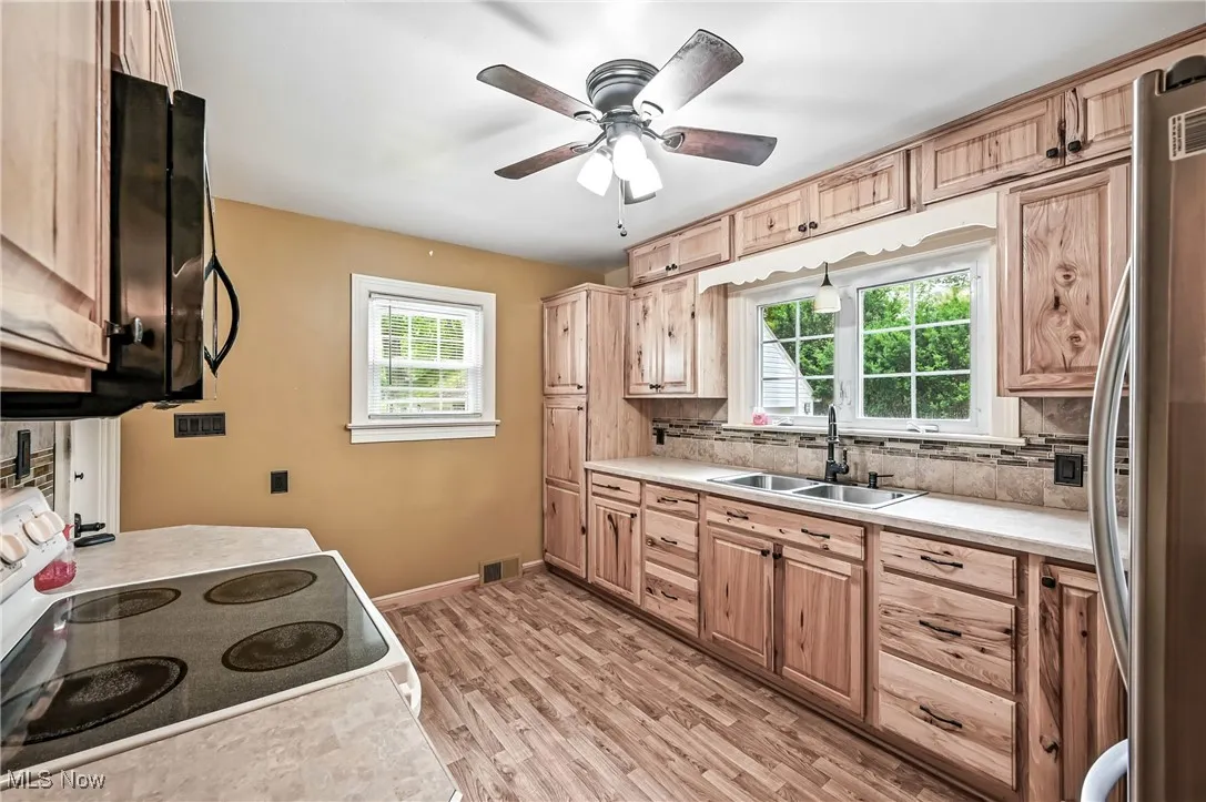 Kitchen with range with electric stovetop, stainless steel refrigerator, light countertops, and tasteful backsplash