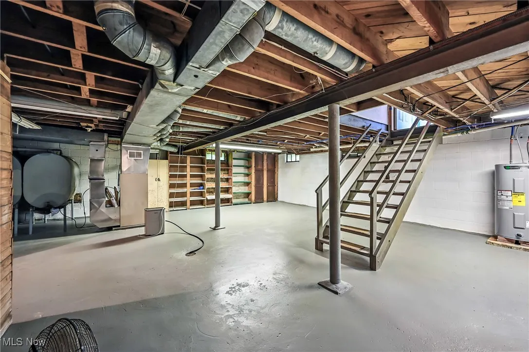 Unfinished below grade area featuring stairway, water heater, heating fuel, and heating unit