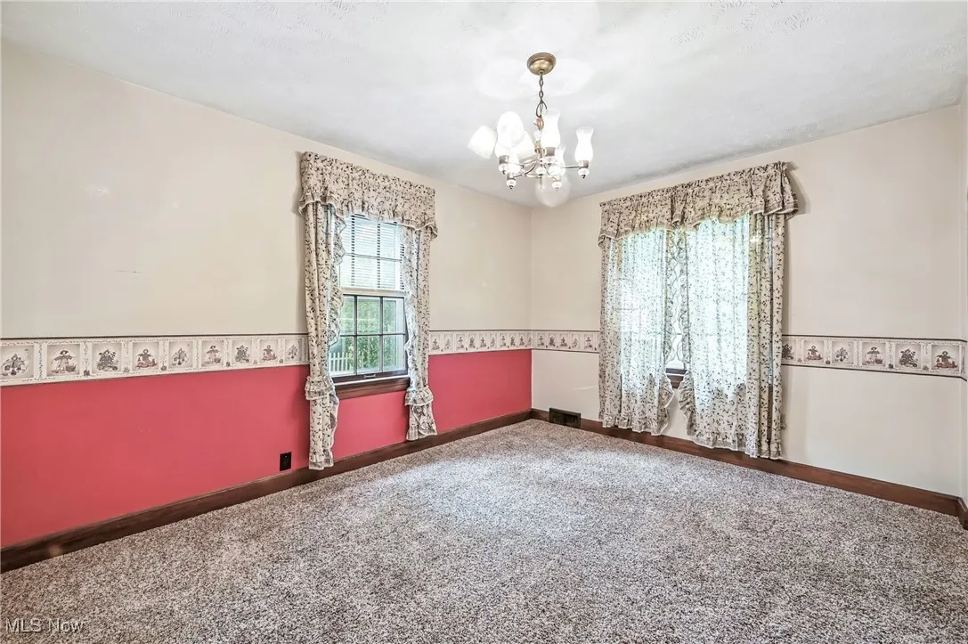 Unfurnished room featuring a chandelier and carpet floors