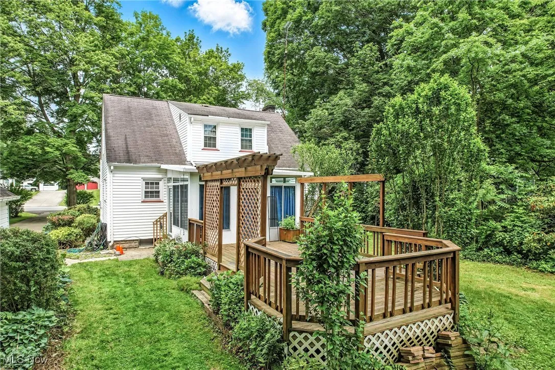 Back of property with a pergola, a deck, roof with shingles, a yard, and a chimney