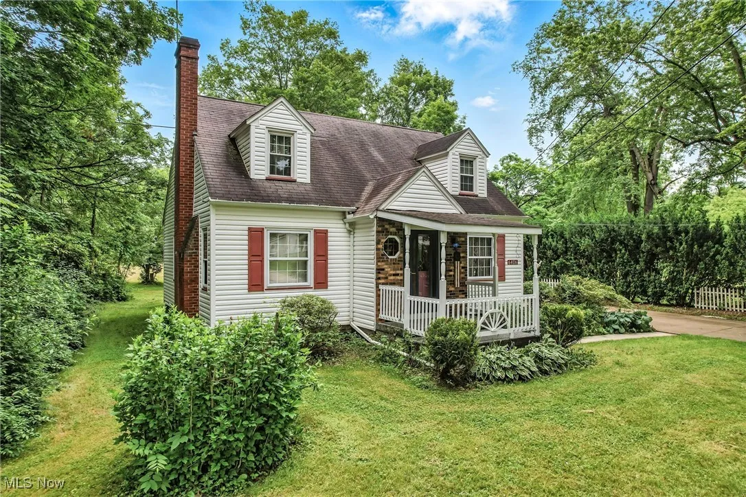 Cape cod house featuring covered porch, a chimney, a front yard, and roof with shingles
