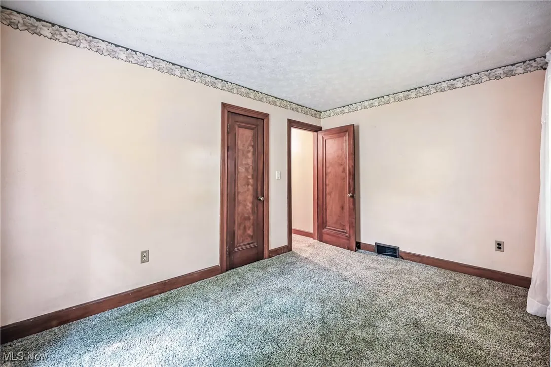 Unfurnished room featuring carpet and a textured ceiling