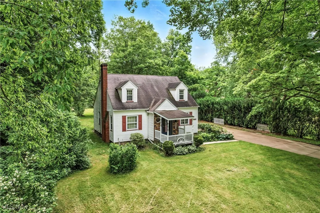 Cape cod-style house with a front lawn, a chimney, and a shingled roof