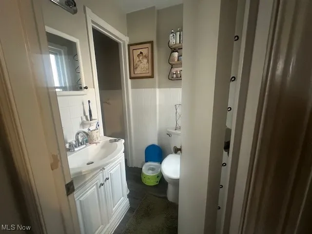Bathroom featuring vanity, a wainscoted wall, and tile walls