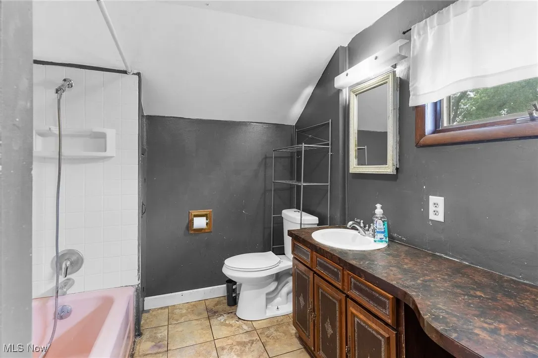 Full bath with lofted ceiling, vanity, and shower / tub combination