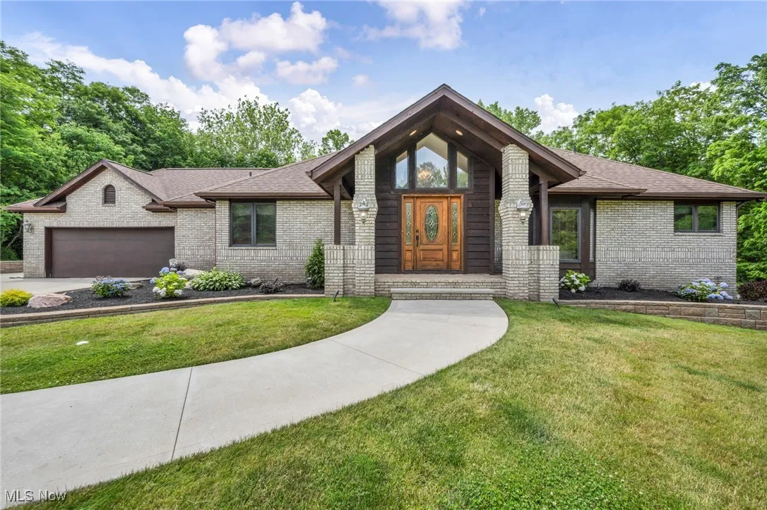 View of front of property featuring brick  a front lawn, an attached garage, and a shingled roof