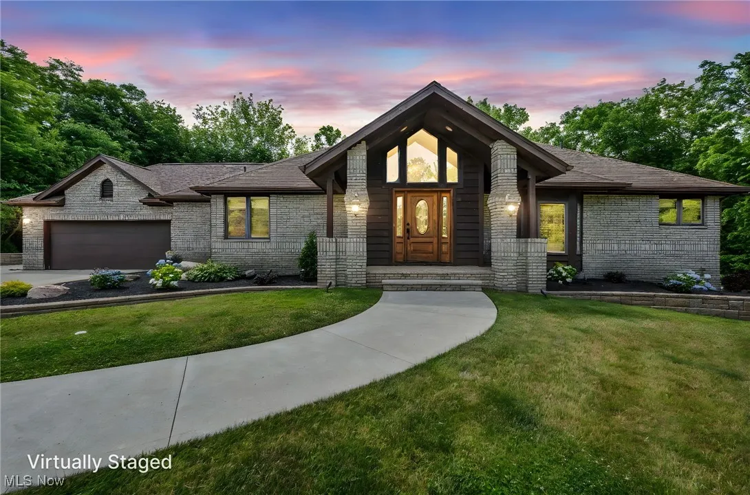 View of front of property with a garage, a front lawn, brick siding, and roof with shingles