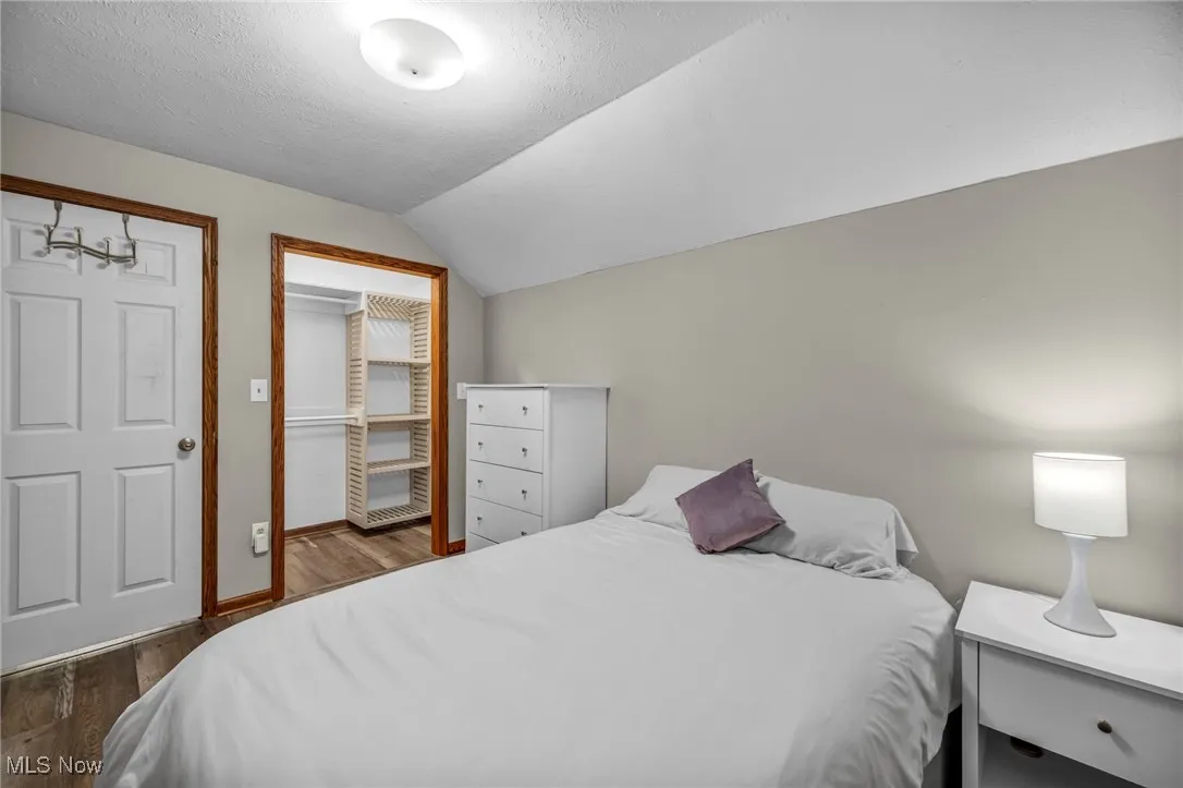 3 rd Bedroom with wood finished floors, vaulted ceiling, and a textured ceiling