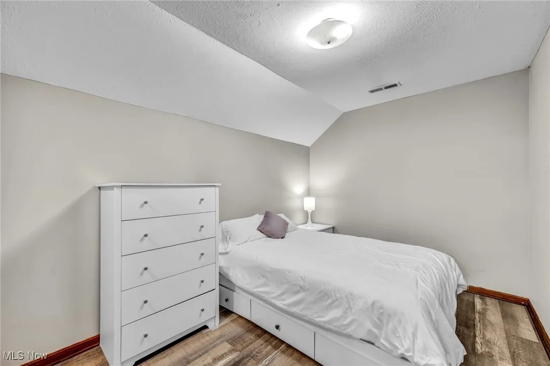 bonus room being used as 5th Bedroom with wood finished floors, lofted ceiling, and a textured ceiling