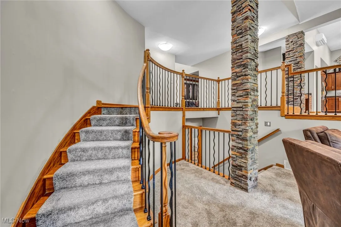 Staircase featuring brick columns and carpet flooring