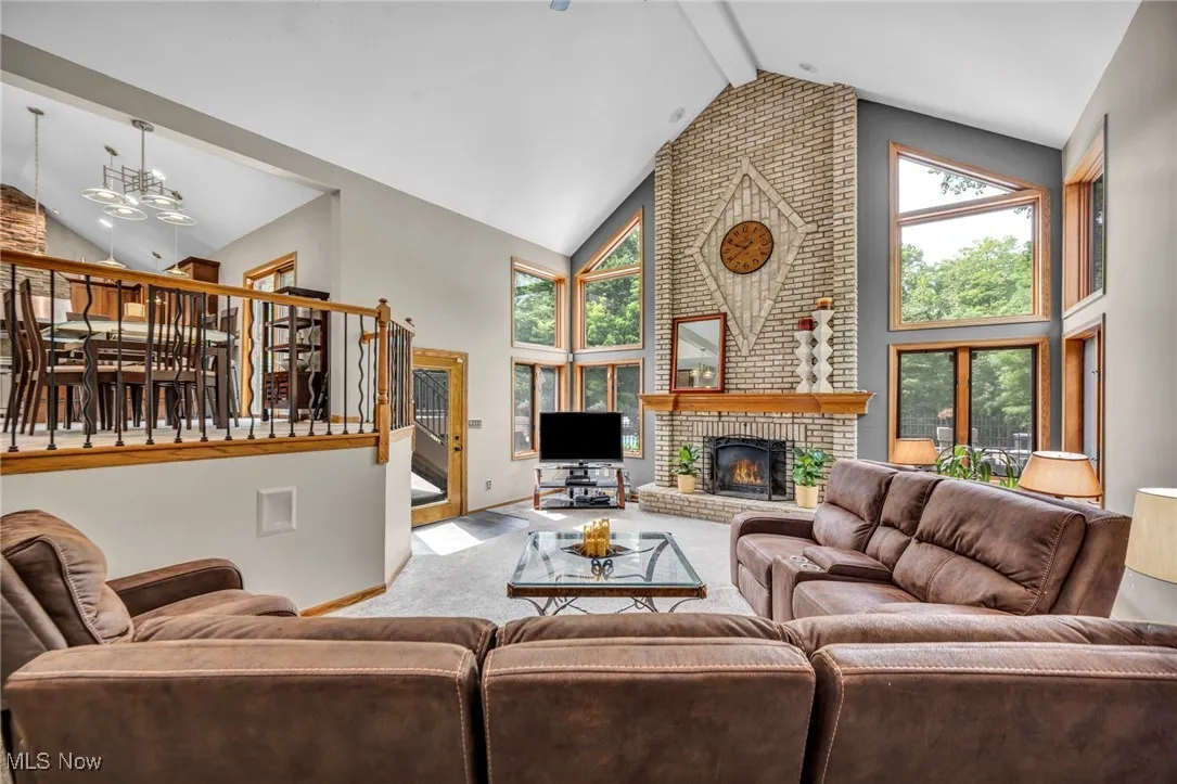 Grate room  area featuring high vaulted ceiling, a fireplace, stairs, plenty of natural light, and carpet floors