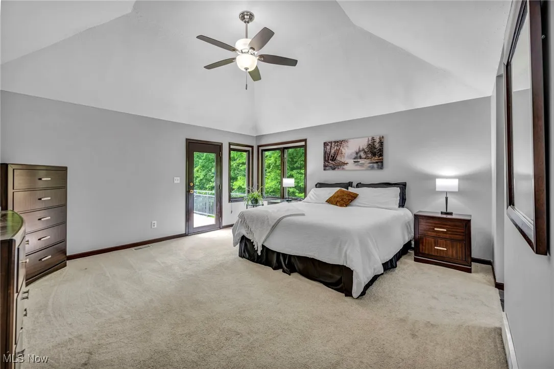 Primary Bedroom featuring light carpet, access to outside, ceiling fan, and high vaulted ceiling