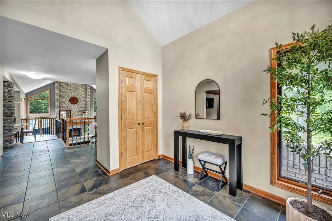 Entrance foyer with dark stone tile flooring and high vaulted ceiling