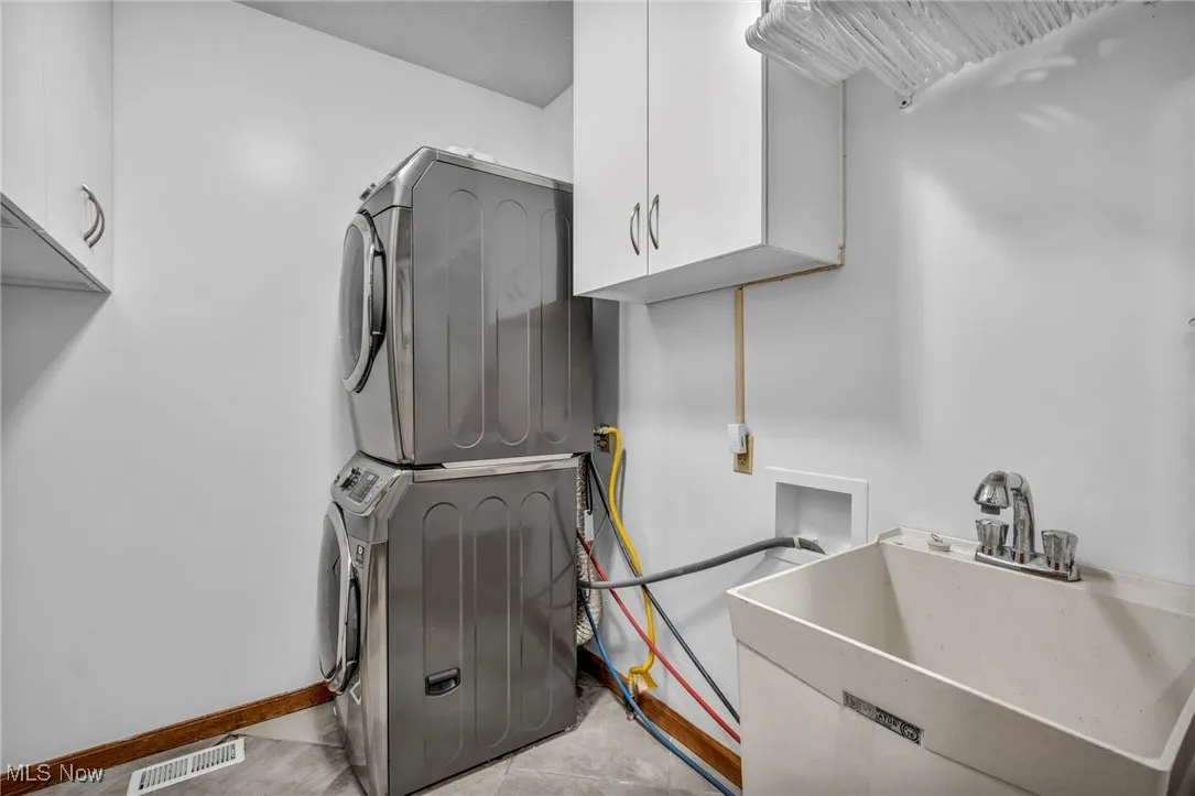 Laundry area with stacked washer / drying machine and cabinet space first floor