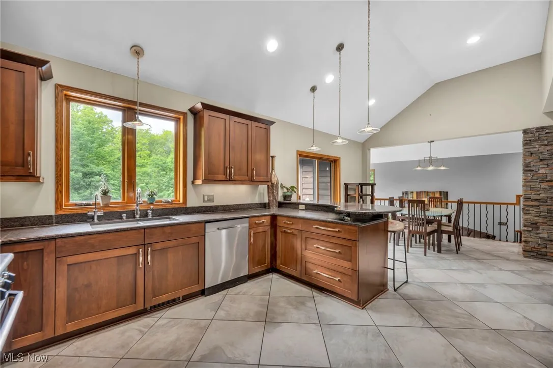 Kitchen with dishwasher, wood cabinetry, , pendant lighting, and  tile patterned floors