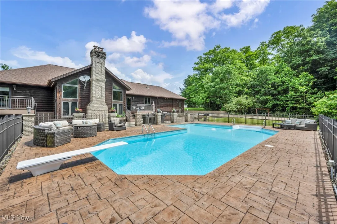 View of swimming pool with an outdoor hangout area, a diving board, and a patio area