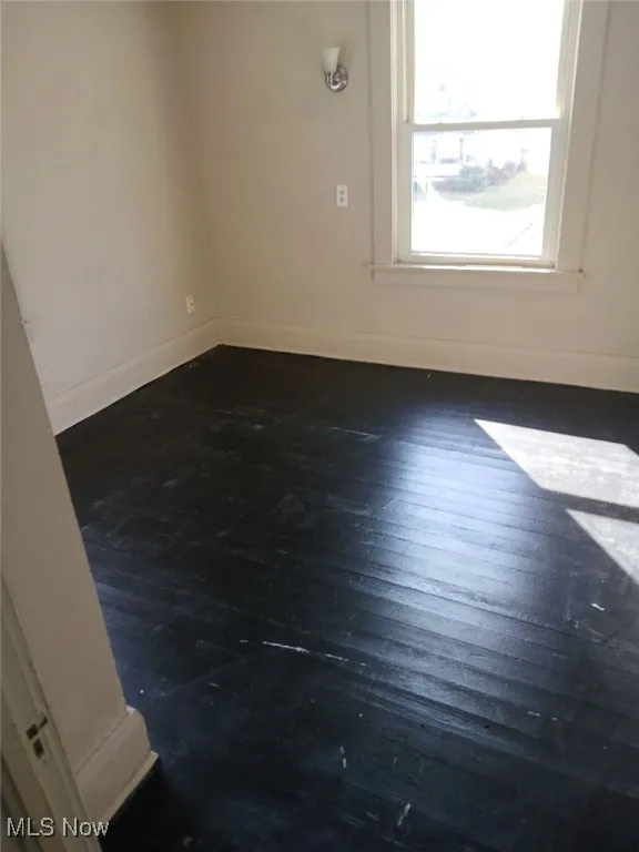 Empty room featuring baseboards and dark wood finished floors