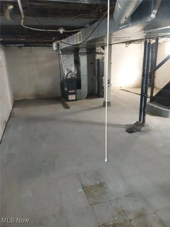 Unfinished basement featuring heating unit and gas water heater