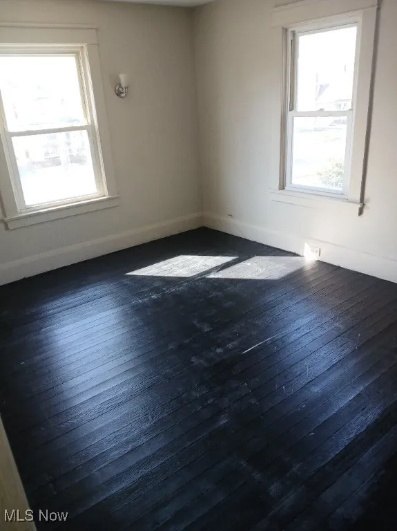 Empty room featuring baseboards and dark wood finished floors