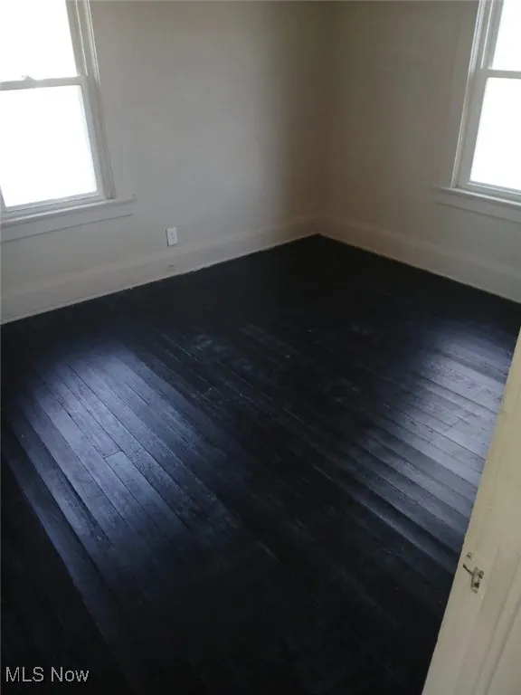 Unfurnished room with dark wood-type flooring and baseboards