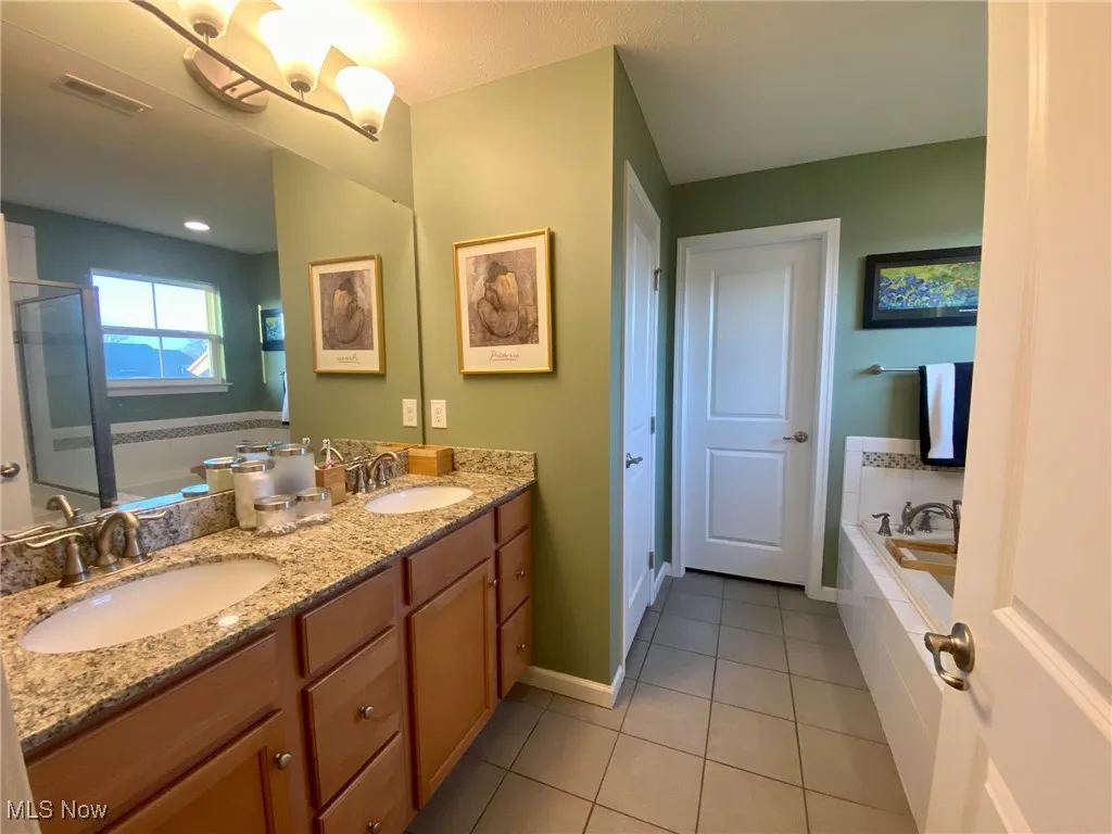 The primary en-suite bathroom is a true luxury, featuring elegant granite countertops and dual sinks for added convenience. Enjoy the separate tiled shower and roomy soaking tub, perfect for unwinding after a long day. For added privacy and function, the bathroom also includes an enclosed toilet and access to the main walk-in closet, creating a spa-like experience right at home.