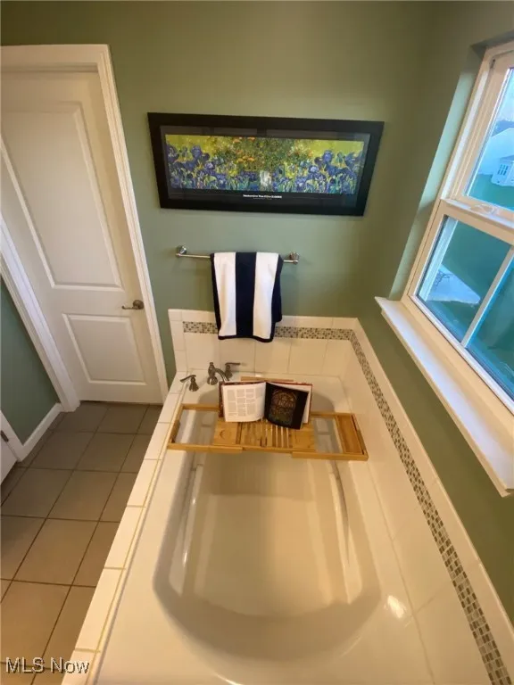 The en-suite bathroom boasts a luxurious soaking tub, elegantly framed with a tile surround. It’s the perfect spot to relax and unwind in style, adding a touch of spa-like serenity to the space.